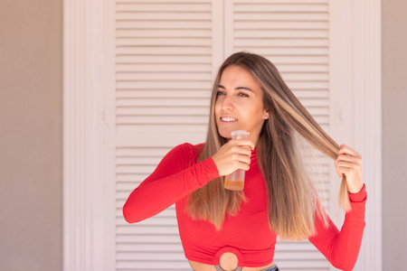 Happy, beautiful and attractive woman looking to the side while appying beauty treatment into her healthy hairの写真素材