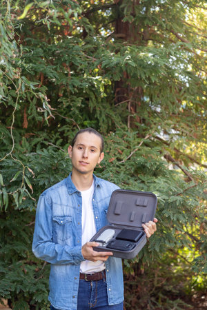 Young man showing a state-of-the-art drone to the camera in his portable briefcase in the middle of...