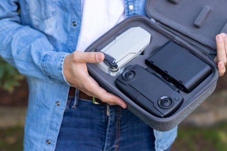 Close portrait of a small portable and foldable grey drone with 4k camera held in the hands of a young manの写真素材