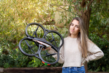 Backlit portrait of a Caucasian girl showing to the camera her new quadricopter drone of initiation in the natureの写真素材