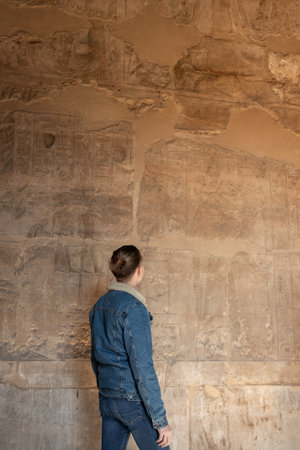 Vertical view of unrecognizable young tourist man looking the hieroglyphics art in the egyptian anciente and historical architectureの写真素材