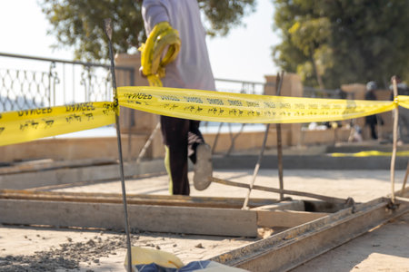 Selective focus of danger yellow cord in a construction site with an unrecognizable man working on itの写真素材