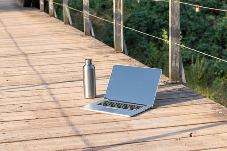 Isolated laptop and bottle of water of a digital nomad on a wooden floor with copy space aroundの写真素材