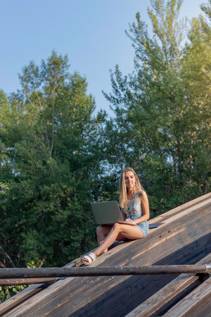 Vertical view of Young woman working as a digital nomad in summer time surrounded by nature and copy space aroundの写真素材