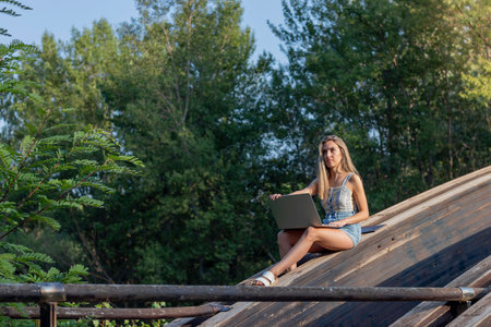 Side view of young woman working as a remote online worker in natural environment in summer time and copy spaceの写真素材