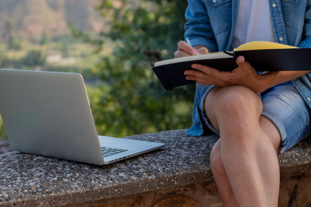 Unrecognizable young man drawing on his notebook about his online entrepreneur project while living abroad in Europeの写真素材