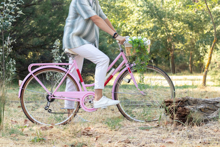 Side view of unrecognizable young hipster man on a pink vintage bike with natural environment in the backgroundの写真素材