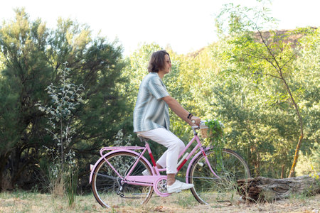 Side view of young man riding a bike through the nature breathing fresh air in spring sunny dayの写真素材