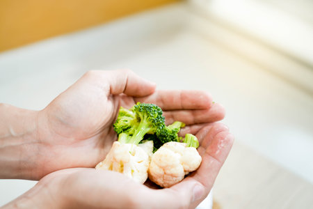 Close up view and selective focus of broccoli and cauliflower vegetables being held by open handsの写真素材