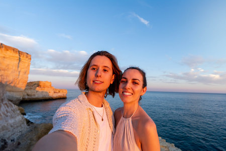 Close-Up of a Couple Taking a Selfie on a Cliff by the Sea at Sunset,の写真素材