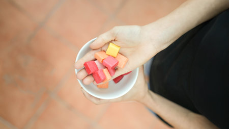 Top close up view of white hands showing colorful candies in a park with left copy spaceの写真素材