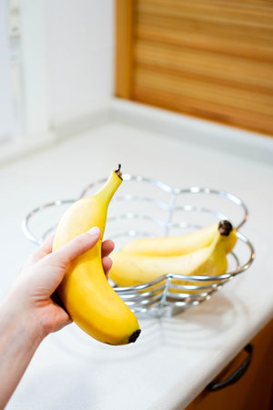 Vertical view of fresh and organic banana in selective focus with a bunch in the background on the top of the counter topの写真素材