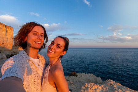 Embracing Love at Sunset: Horizontal selfie Capturing a Couple Intimate Moment on a Rocky Cliffの写真素材