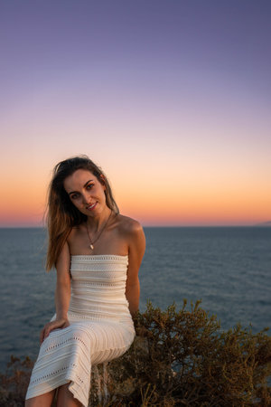 Vertical view of Peaceful Contemplation at beautiful and unique Dusk: A Young blonde Woman in a White Dress looking to cameraの写真素材