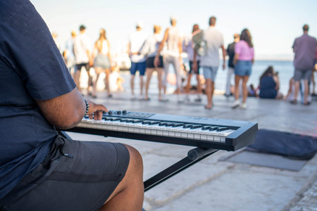 A Serene Sunset Serenade: A Street Musician Melody Echoes on a Bustling Boardwalk, His Fingers Dancing on the Keyboard, Unseen Faces Passing By, All Underneath the Warm,の写真素材