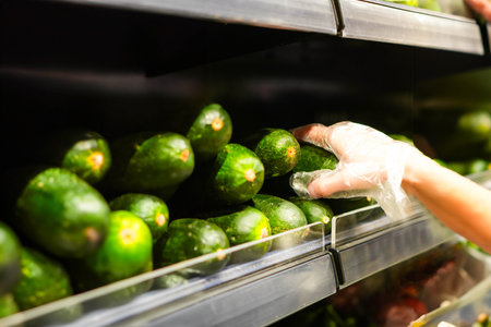 Unrecognizable woman hand taking and choosing fresh green zucchini from a pile in the supermarketの写真素材