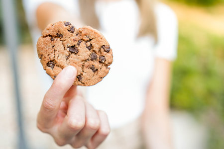 Closeup view of blurred young woman showing to camera delicious good looking chocolate chips cookieの写真素材
