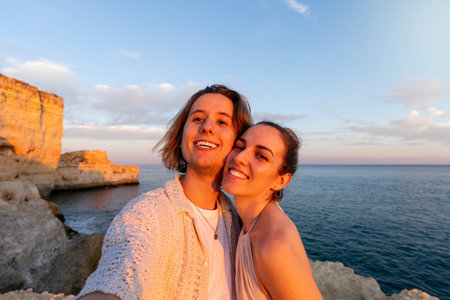 Embracing Love at Sunset: A Close-Up, selfie of a Couple on a Cliff Overlooking the Ocean at Sunset while on summer holidays.の写真素材