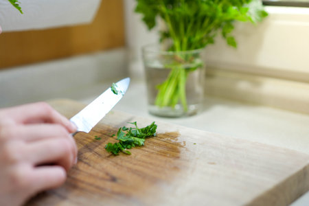 Selective focus on hand chopping parsley for seasoning in a vegetarian or vegan mealの写真素材