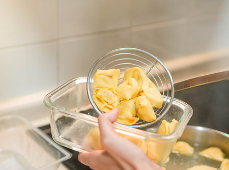 Close up view of hand taking ravioli pasta with a skimmer spoon after boiling themの写真素材