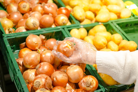 Close up view of unrecognizable woman picking onions in a grocery store, personal perspective point of view.の写真素材