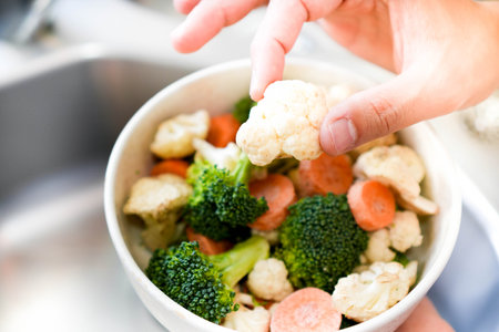 Top close up view of mixed fresh raw vegetables in white ceramic bowl in a house kitchenの写真素材