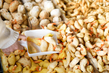 Close up view of people choosing raw or undone tempura shrimp, breaded, crispy, deep fried in batter.の写真素材