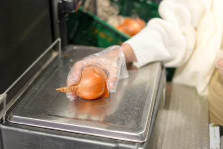 Close up side view of unrecognizable young woman placing an onion to weight on a self-service scales