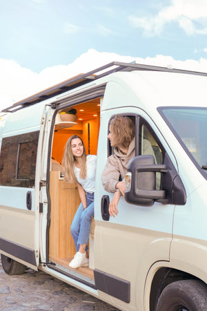 A young couple is seen cherishing a moment together inside their modern luxury campervan, symbolizing adventure and a carefree lifestyle.の写真素材