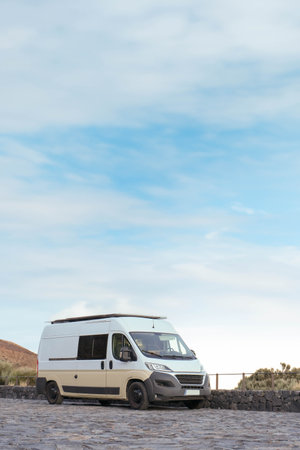 A white van is stationary on a rugged cobblestone road amidst a serene natural setting, suggesting a...