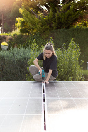 Vertical front view of young engineer woman working service checking installation solar cell on the roof with vegetationの写真素材
