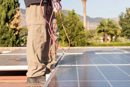 Cropped view of young woman working as electrician with red wire hanging in a solar panel installation jobの写真素材