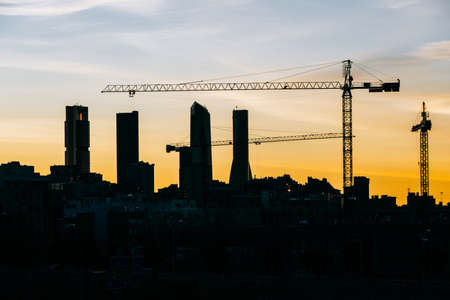 Cuatro Torres Business Area Madrid skyline at sunset with construction cranes and residential buildings in a close view. Orange tones and contast.の写真素材