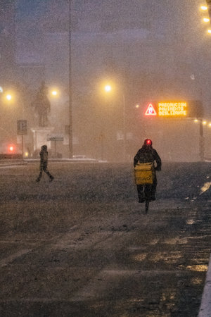 Madrid, Spain - January 2021: Glovo (food delivery company) rider in Alacala street with hevy snow...