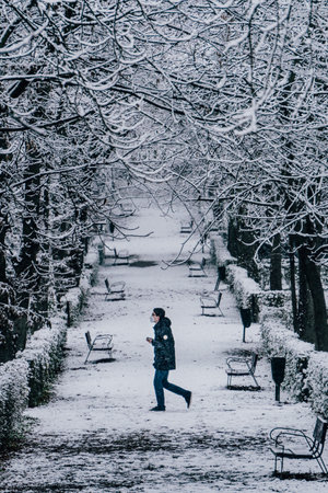 Madrid, Spain - January 2021: young boy walking from right to left in Retiro park covered in snow due to Filomena Storm. Heavy snow.のeditorial素材