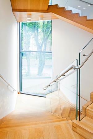 Modern architecture interior with elegant wooden stairs and glass balustradeの写真素材