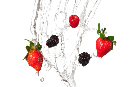 Strawberries & blackberries splashing through water.の写真素材