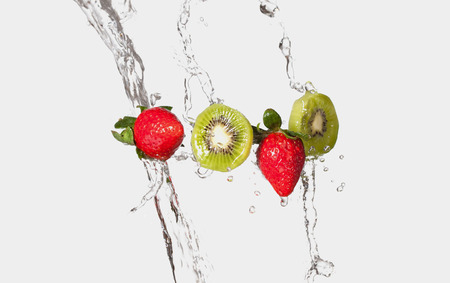 Strawberries & kiwi fruit splashing through water.の写真素材