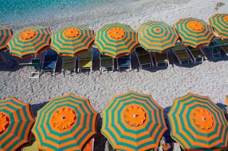 Rows of orange & green umbrellas on the beachの写真素材