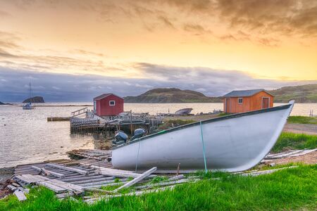 Boats and sheds in coastal fishing village during sunset in Newfoundland, Canadaの写真素材