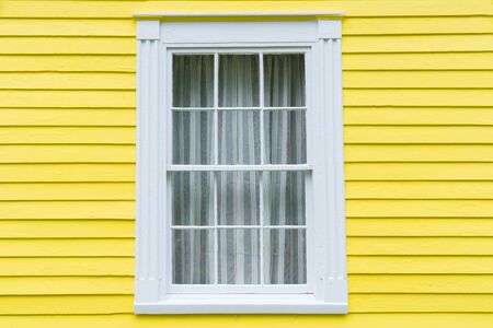 Old wood frame window with bright yellow clapboard sidingの写真素材