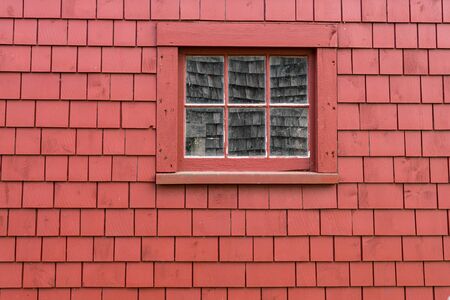Small old wooden window on the exterior of a red shingle wallの写真素材