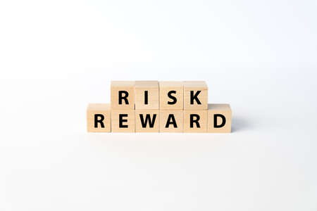 The concepts of Risk and Reward spelled out with wooden blocks on a white background