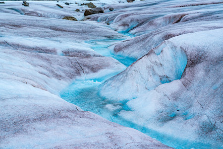 Melting glacier ice in the Mendenhall Glacier in Alaska forms a winding stream of crystal clear blue waterの写真素材