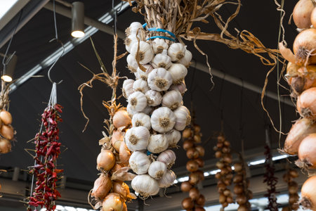 Bundles of garlic, onions and peppers hanging in a farmers market in Portugalの写真素材