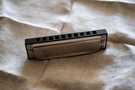 chromed harmonica on light linenの写真素材