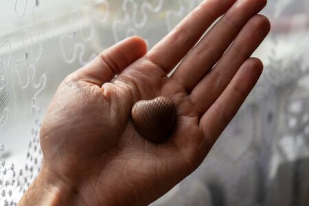 Chocolate heart in the palm of your handの写真素材