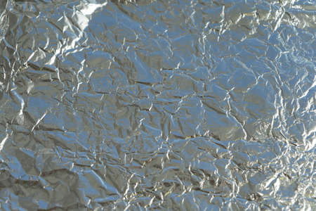 Shiny aluminum foil background. Metal silver crumpled and creased tinfoil with copy space.