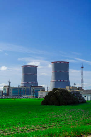 Belarusian Nuclear power plant. Green field and haystacks on the background of Nuclear power plant