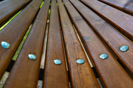 elements of the bench. Wooden slats with metal nails with round cap. Selective focus. bench in the...
